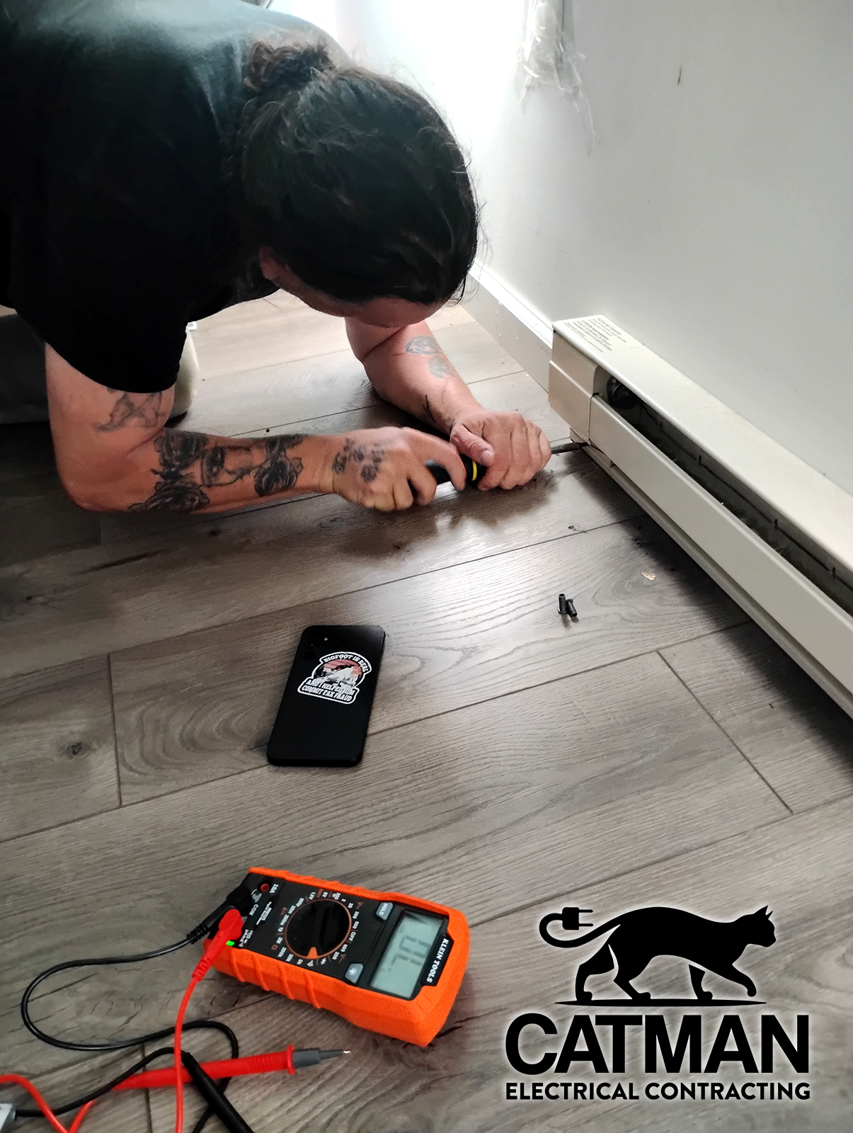 Electrician repairing baseboard heat with meter